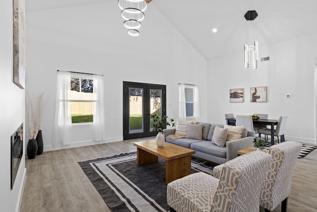 living room with a chandelier, light hardwood / wood-style floors, and high vaulted ceiling