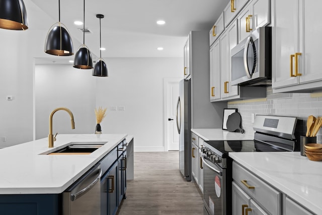 kitchen with sink, hanging light fixtures, stainless steel appliances, hardwood / wood-style floors, and a center island with sink