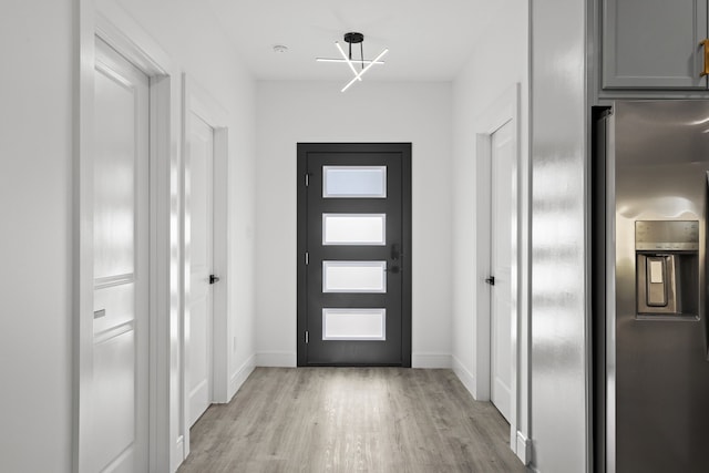 doorway featuring light hardwood / wood-style flooring and a notable chandelier