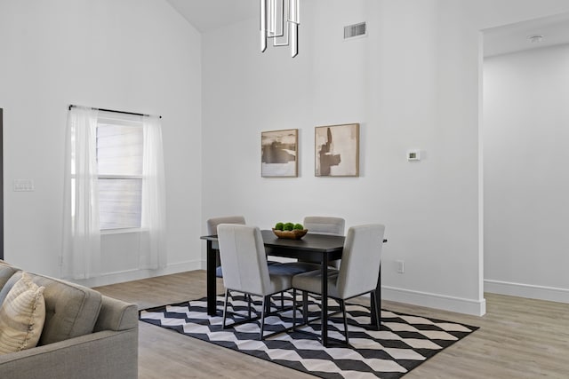 dining area with a towering ceiling and light hardwood / wood-style floors