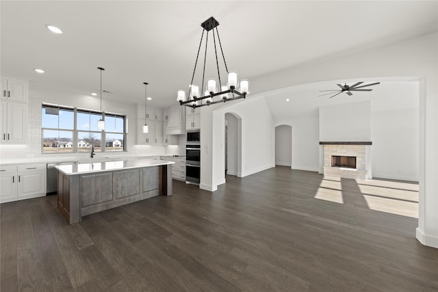 kitchen featuring a center island, white cabinets, ceiling fan, built in microwave, and decorative light fixtures