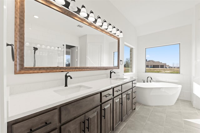 bathroom featuring a bath, vanity, tile patterned floors, and tile walls