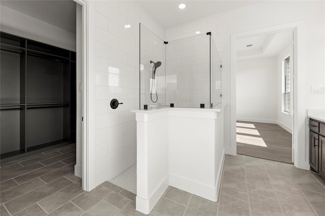 bathroom with a tile shower, vanity, and wood-type flooring