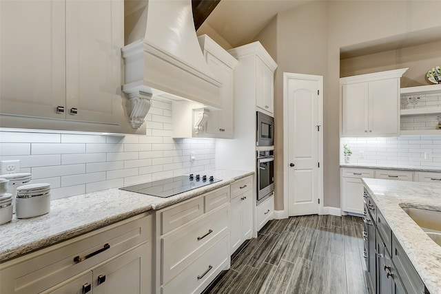 kitchen featuring stainless steel appliances, white cabinetry, premium range hood, and light stone counters