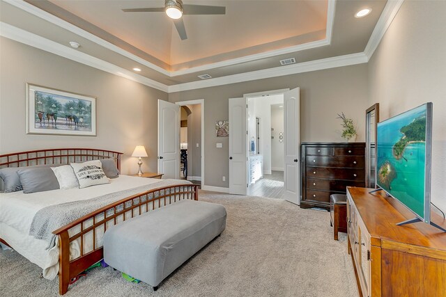 bedroom featuring light colored carpet, ceiling fan, crown molding, and a tray ceiling