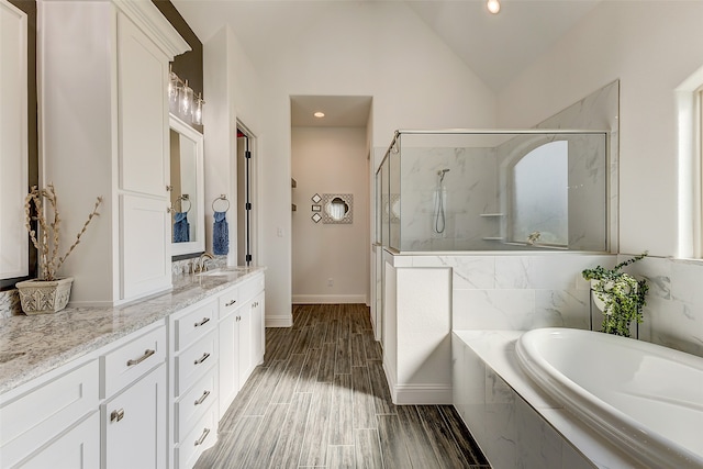 bathroom with plus walk in shower, vanity, hardwood / wood-style flooring, and lofted ceiling