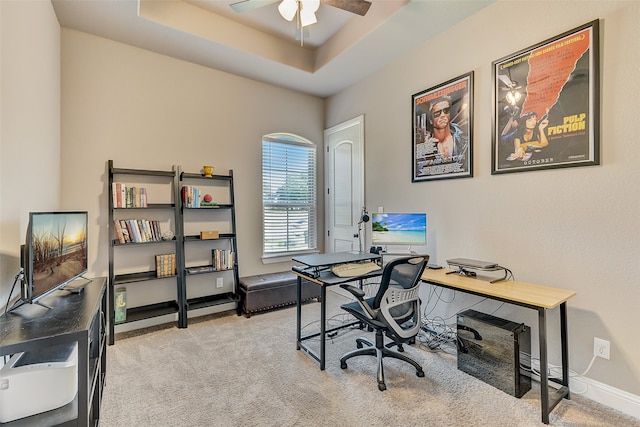 carpeted office space featuring ceiling fan and a raised ceiling