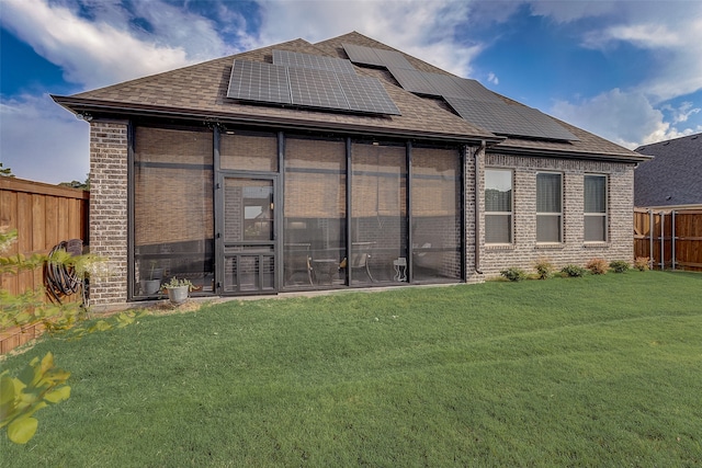 rear view of property featuring solar panels and a yard