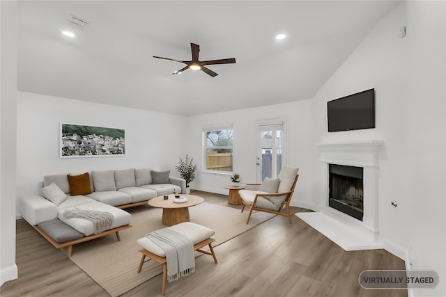 living room featuring ceiling fan, light hardwood / wood-style floors, and vaulted ceiling