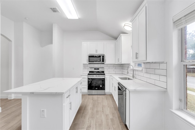 kitchen featuring white cabinetry, a center island, sink, stainless steel appliances, and light hardwood / wood-style floors