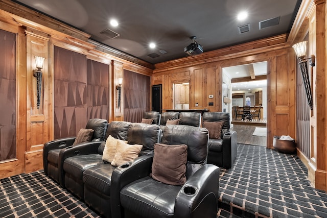 carpeted home theater room with ornamental molding and wooden walls