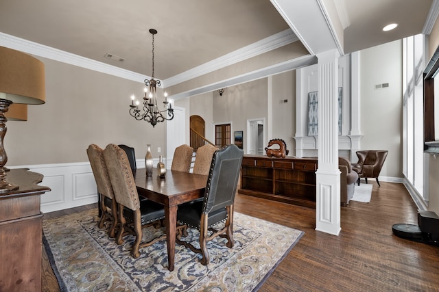 dining space with a notable chandelier, crown molding, dark wood-type flooring, and decorative columns