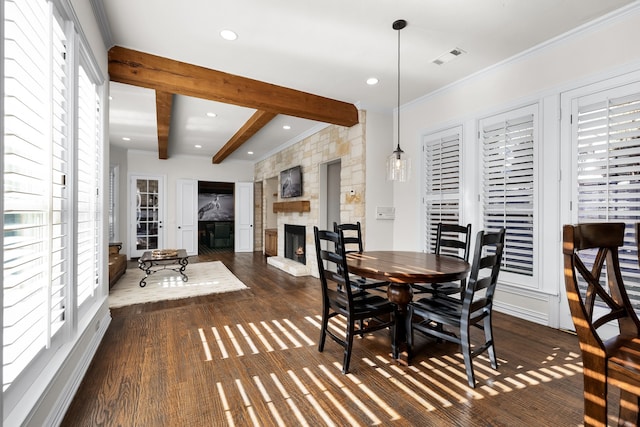 dining space with beam ceiling, a stone fireplace, dark hardwood / wood-style flooring, and ornamental molding