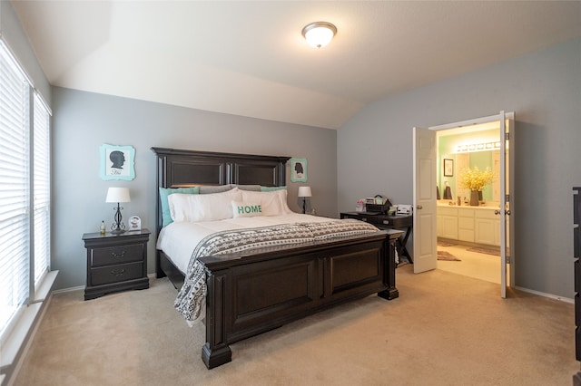 carpeted bedroom featuring ensuite bathroom, multiple windows, and lofted ceiling