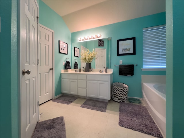 bathroom with a bathtub, vanity, vaulted ceiling, and tile patterned flooring