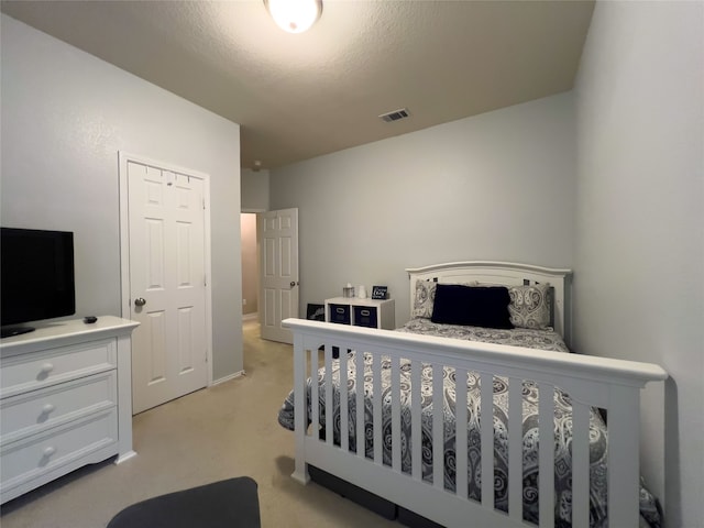 bedroom with a closet, light colored carpet, and a textured ceiling