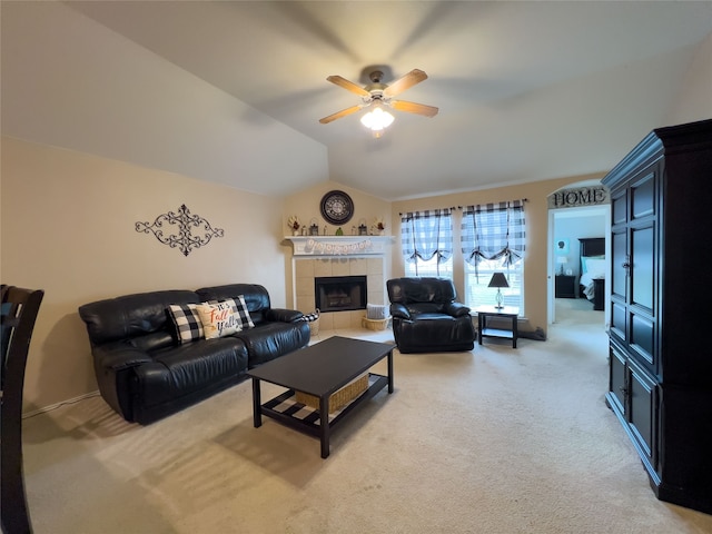 living room with ceiling fan, a tiled fireplace, carpet floors, and vaulted ceiling