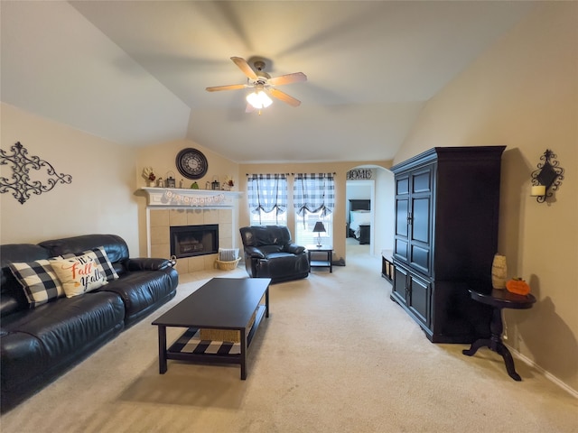 living room with ceiling fan, carpet floors, a tile fireplace, and vaulted ceiling