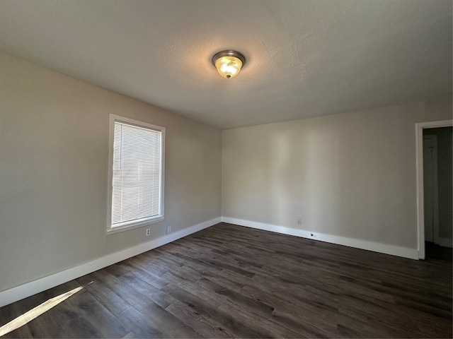 spare room featuring a textured ceiling and dark hardwood / wood-style floors