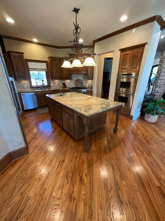 kitchen with a spacious island, stainless steel appliances, hanging light fixtures, and dark wood-type flooring