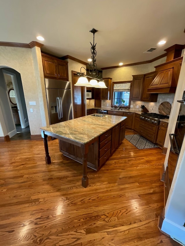 kitchen with light stone countertops, sink, dark wood-type flooring, a breakfast bar, and a kitchen island