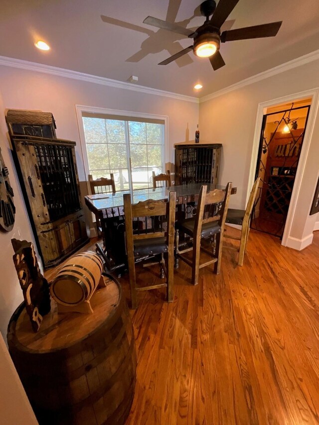 dining space featuring wood-type flooring, ceiling fan, and ornamental molding