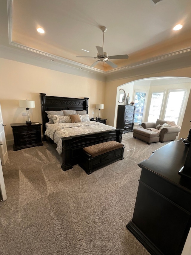 carpeted bedroom with a tray ceiling, ceiling fan, and ornamental molding