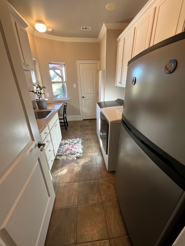 kitchen with stainless steel refrigerator, washer / clothes dryer, and white cabinets