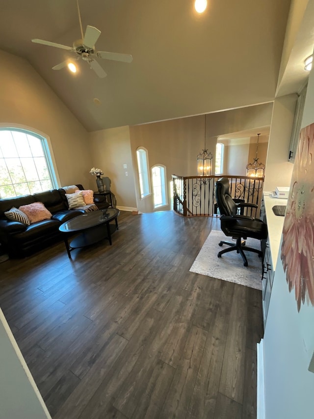 living room with plenty of natural light, dark hardwood / wood-style flooring, ceiling fan with notable chandelier, and high vaulted ceiling