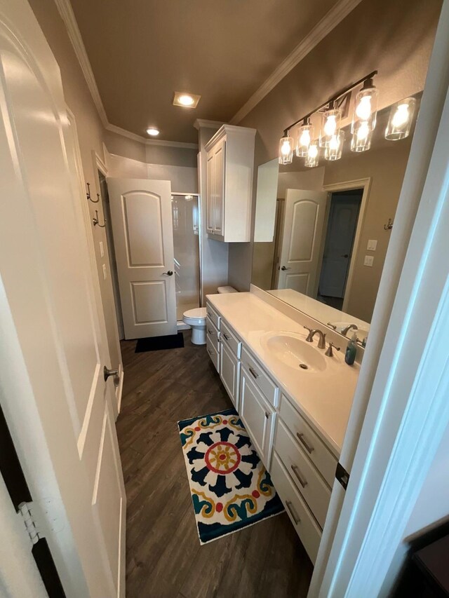 bathroom featuring hardwood / wood-style floors, vanity, crown molding, toilet, and walk in shower