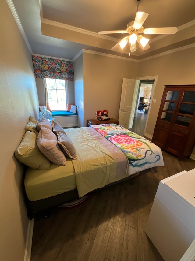 bedroom with ornamental molding, a tray ceiling, ceiling fan, and dark wood-type flooring