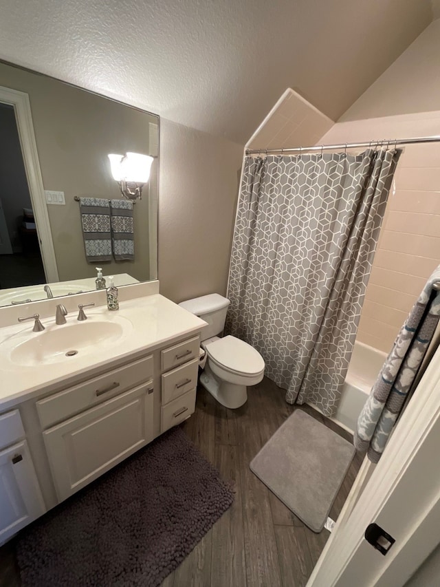 full bathroom featuring hardwood / wood-style floors, a textured ceiling, toilet, shower / bath combo with shower curtain, and vanity