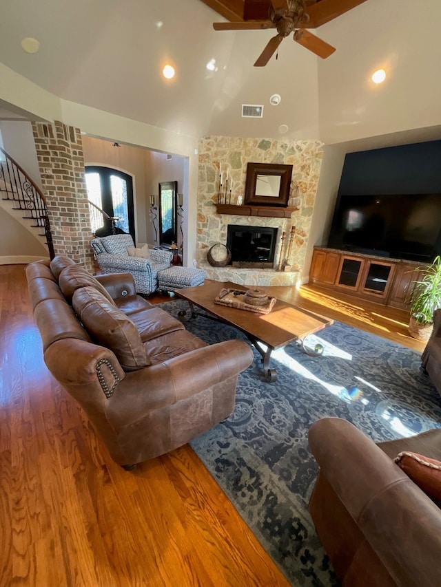 living room featuring hardwood / wood-style floors, ceiling fan, a fireplace, and high vaulted ceiling