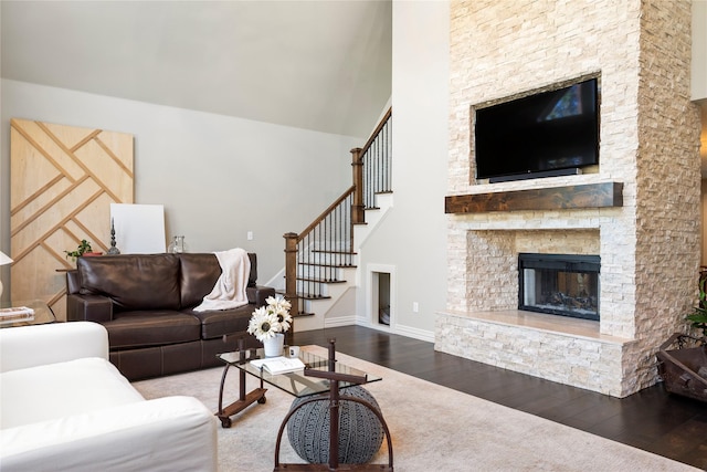 living room with a towering ceiling, hardwood / wood-style floors, and a fireplace