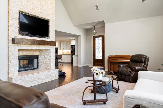 living room featuring a stone fireplace, hardwood / wood-style floors, and high vaulted ceiling