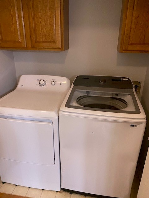 laundry area with cabinets, light tile patterned flooring, and washing machine and dryer