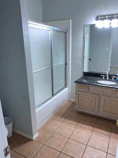 bathroom featuring tile patterned flooring, vanity, and enclosed tub / shower combo