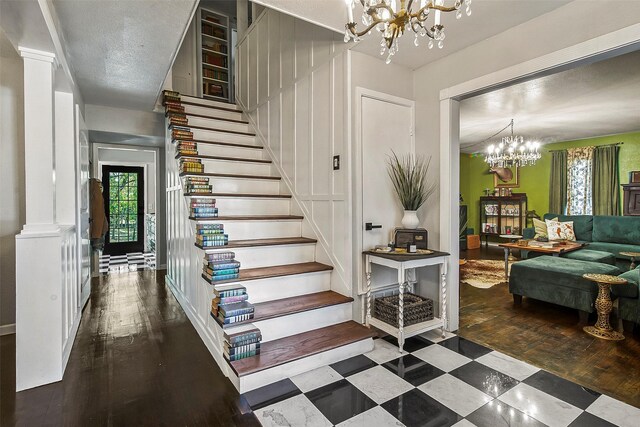 staircase with hardwood / wood-style flooring, a chandelier, and ornate columns