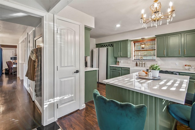 kitchen featuring sink, green cabinetry, decorative light fixtures, dark hardwood / wood-style flooring, and decorative backsplash