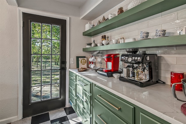 bar featuring green cabinets, backsplash, and light stone counters