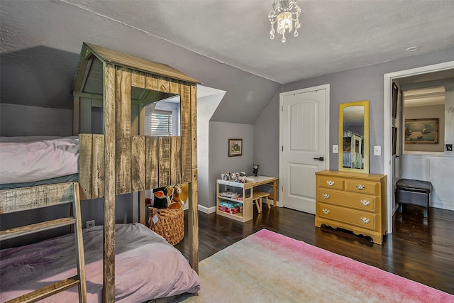 bedroom with an inviting chandelier, dark wood-type flooring, a textured ceiling, and vaulted ceiling