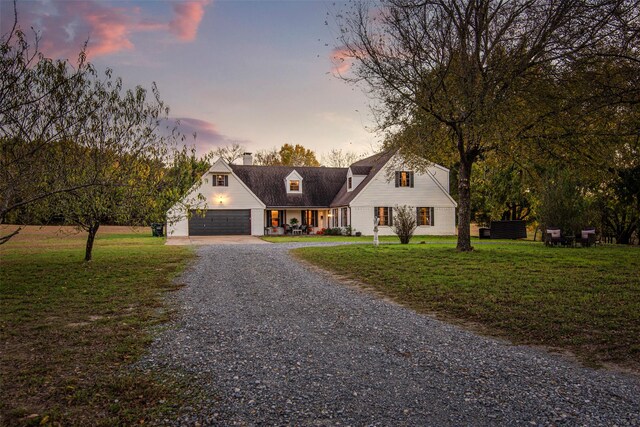 cape cod-style house featuring a yard and a garage