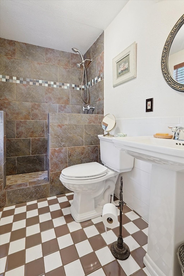 bathroom featuring a tile shower, a textured ceiling, and toilet