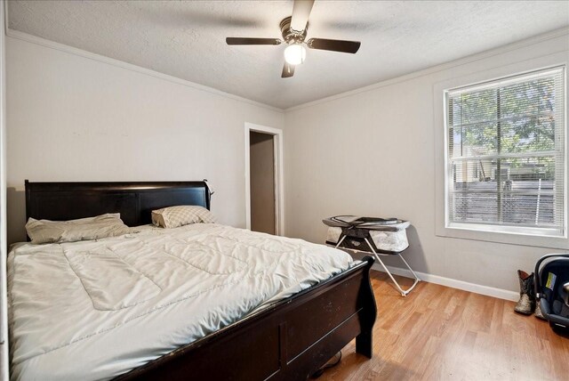 bedroom with ceiling fan, crown molding, light hardwood / wood-style floors, and a textured ceiling