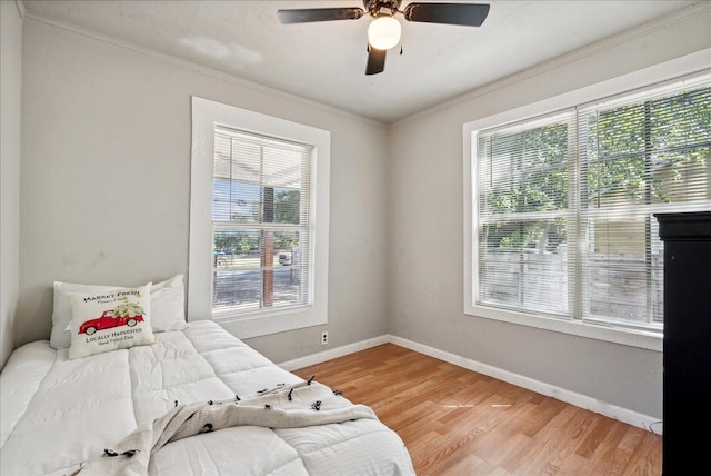 bedroom featuring light hardwood / wood-style flooring, ceiling fan, and ornamental molding