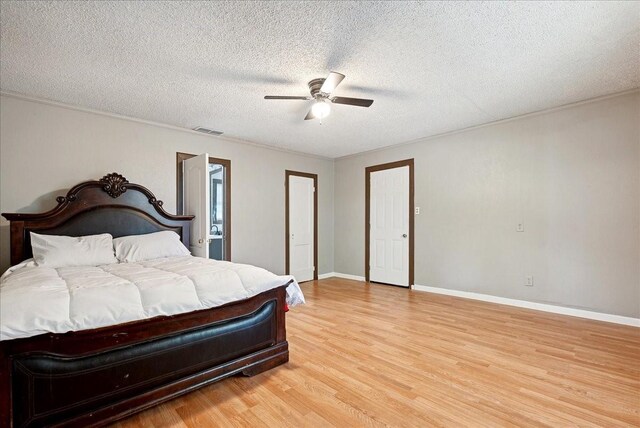 bedroom with a textured ceiling, light hardwood / wood-style flooring, ceiling fan, and connected bathroom