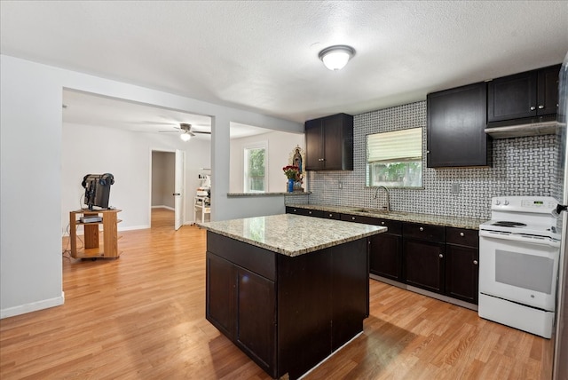 kitchen featuring white electric range, light hardwood / wood-style flooring, decorative backsplash, a textured ceiling, and a kitchen island