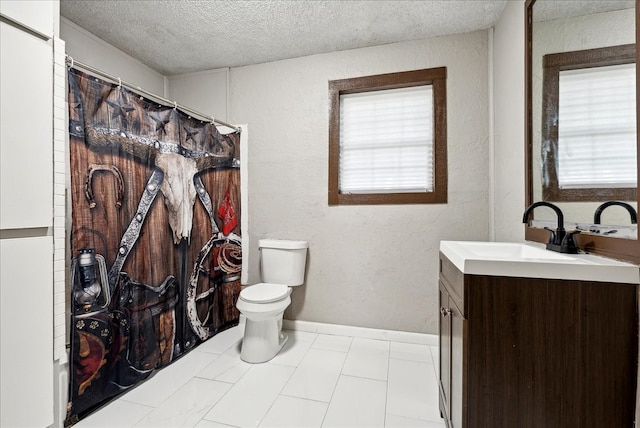 bathroom with a textured ceiling, vanity, toilet, and a healthy amount of sunlight