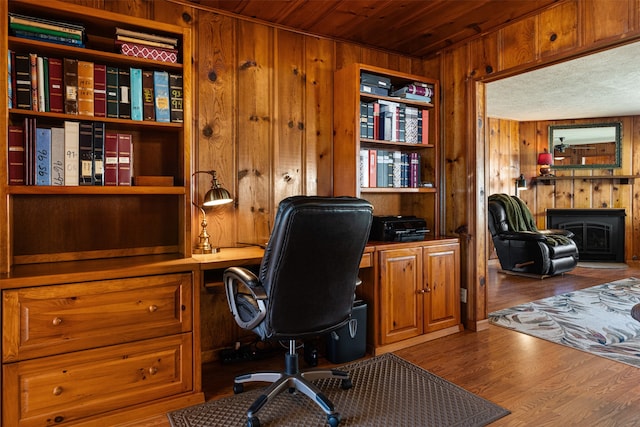 office with hardwood / wood-style flooring, a wood stove, wooden ceiling, and wood walls