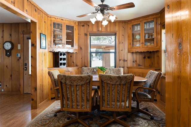 dining room with wood walls, ceiling fan, and hardwood / wood-style flooring